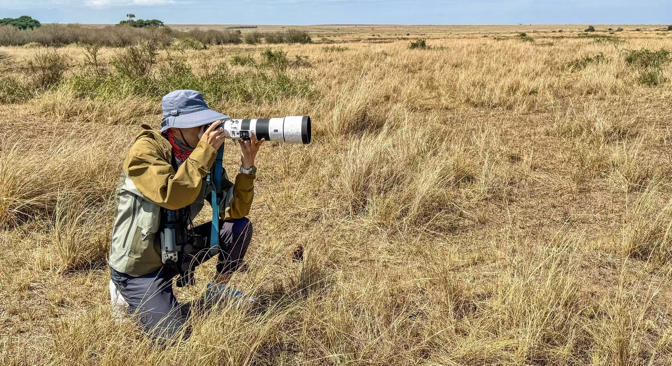 Boone Wang kneeling in the grass with a telephoto lens